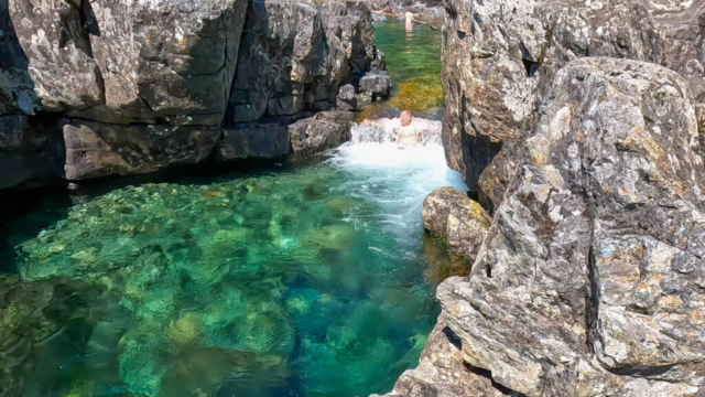 In a waterfall at ?a?ukmin Tribal Park, aka Wally Creek. Clear water and a small waterfall with me underneath it.